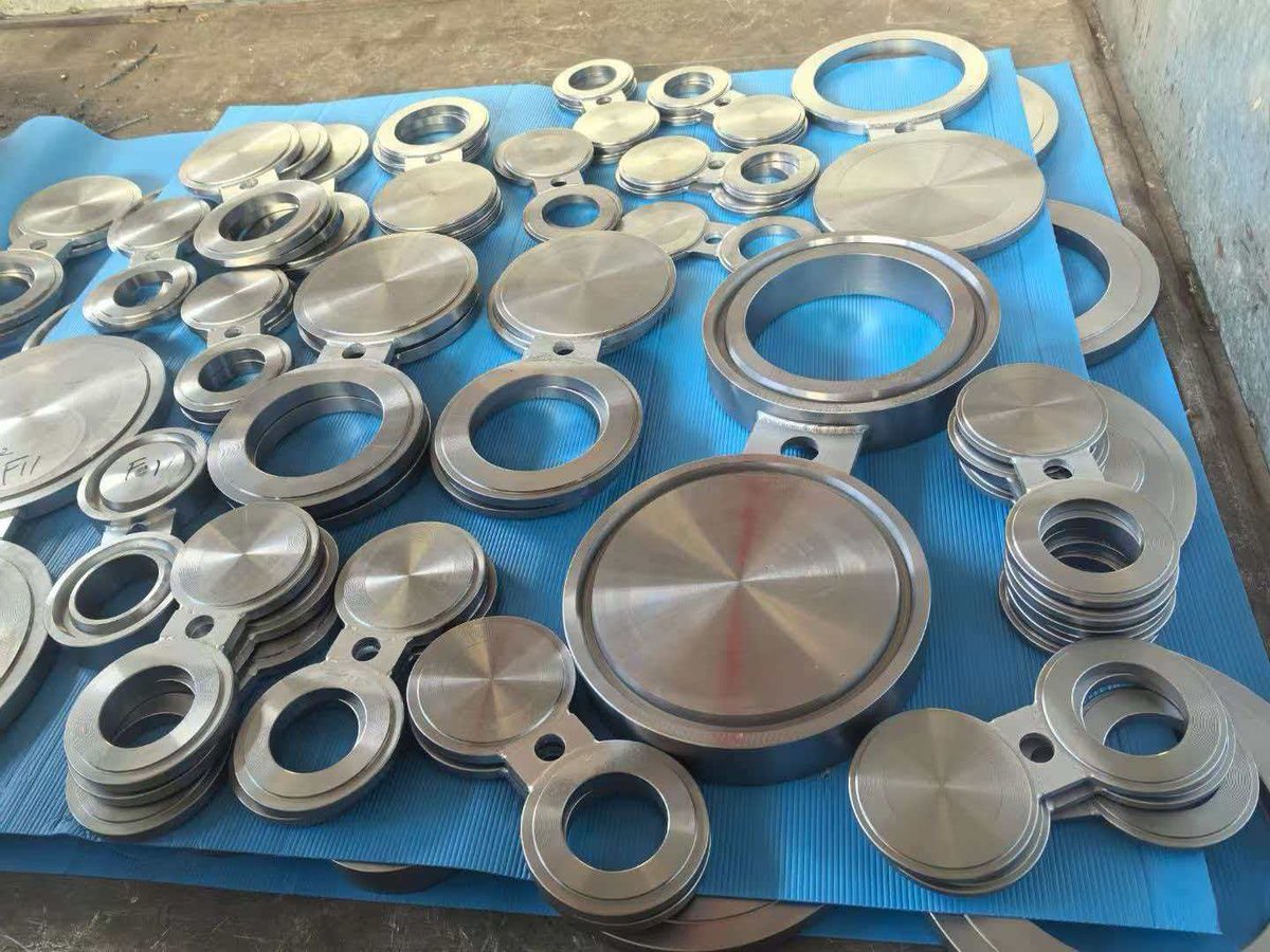 Blind and slip-on flanges arranged on display mat in workshop