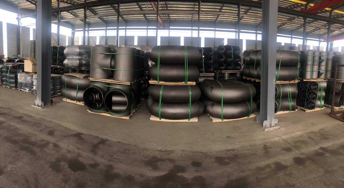 Pipe fittings — elbows, tees and reducers stacked on pallets in manufacturing warehouse